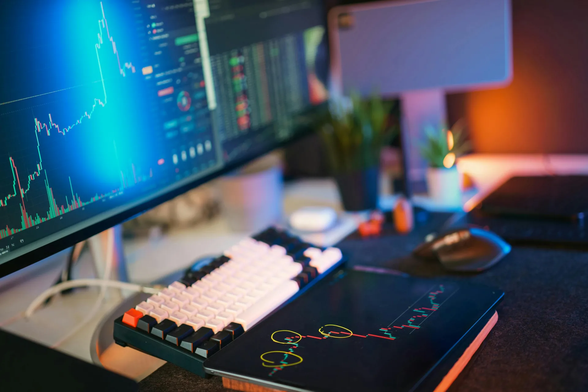 Dark workspace with monitors displaying live dashboards and analytics, warm rim light along the right edge